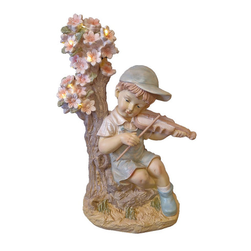 Boy plays Violin Beside Solar Lighting Cherry Tree